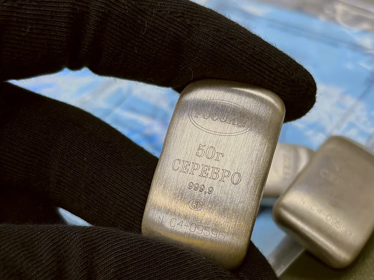 Серебряный слиток 50 г в руке оценщика